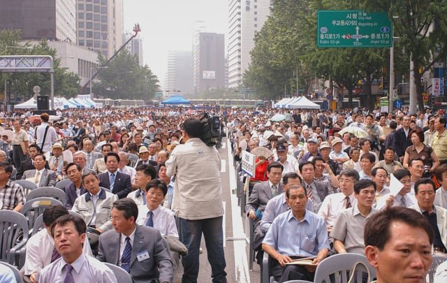 Thousands gathered in downtown Seoul for the groundbreaking ceremony of the Cheonggyecheon restoration project, a massive urban renewal initiative that replaced a congested elevated highway with a seven-mile-long public park, uncovering a historic stream buried under concrete since the 60s. (2003)